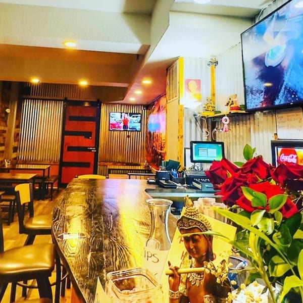 Interior of 9 Thai Restaurant with a bar, dining tables, and decorative Buddha statue with red roses.