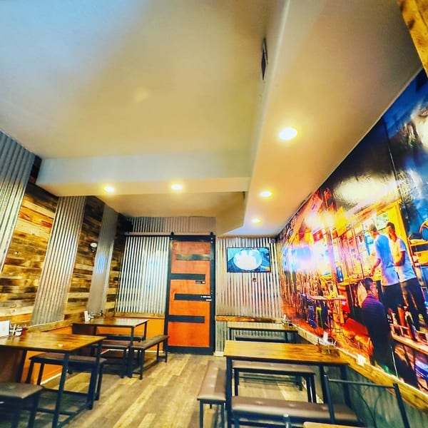 Interior of 9 Thai Restaurant with wooden tables, benches, and a vibrant mural on one wall.
