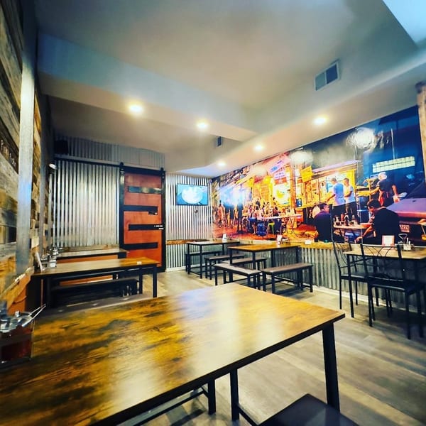 Interior of 9 Thai Restaurant with wooden tables, benches, and a large mural of a bustling street scene.