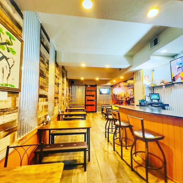 Interior of 9 Thai Restaurant with wooden tables, benches, bar stools, and corrugated metal walls.