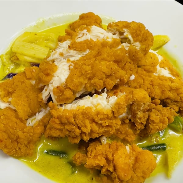 Crispy fried chicken pieces served over a vibrant yellow curry with vegetables at 9 Thai Restaurant.