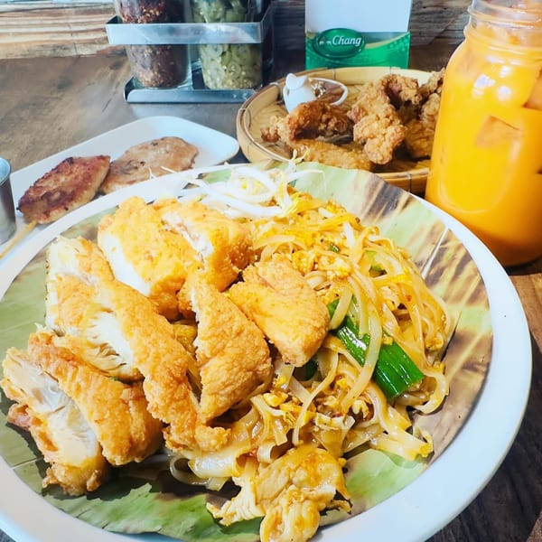 Pad See Ew with crispy fried chicken, a side of fried chicken, and Thai iced tea.